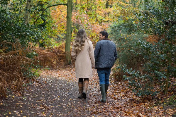 Engaged couple walking through autumn leaves